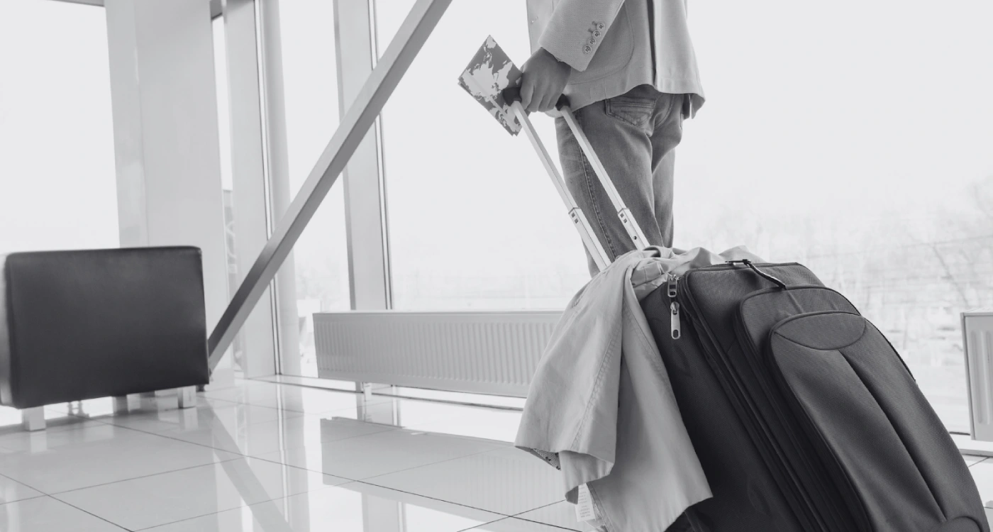 Person with suitcase and passport at airport terminal