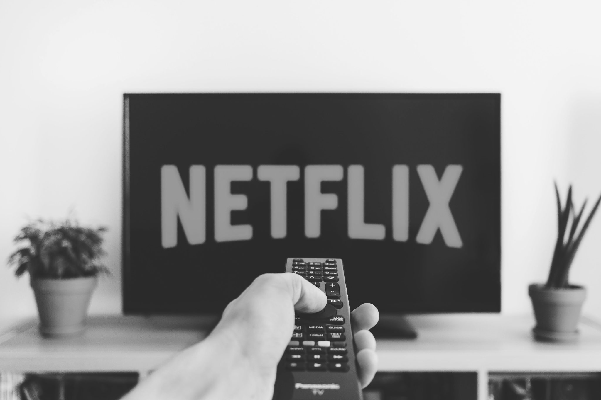 A person pointing a remote to a tv with the Netflix logo illustrating The Growing Popularity of Subscription Services in South Africa